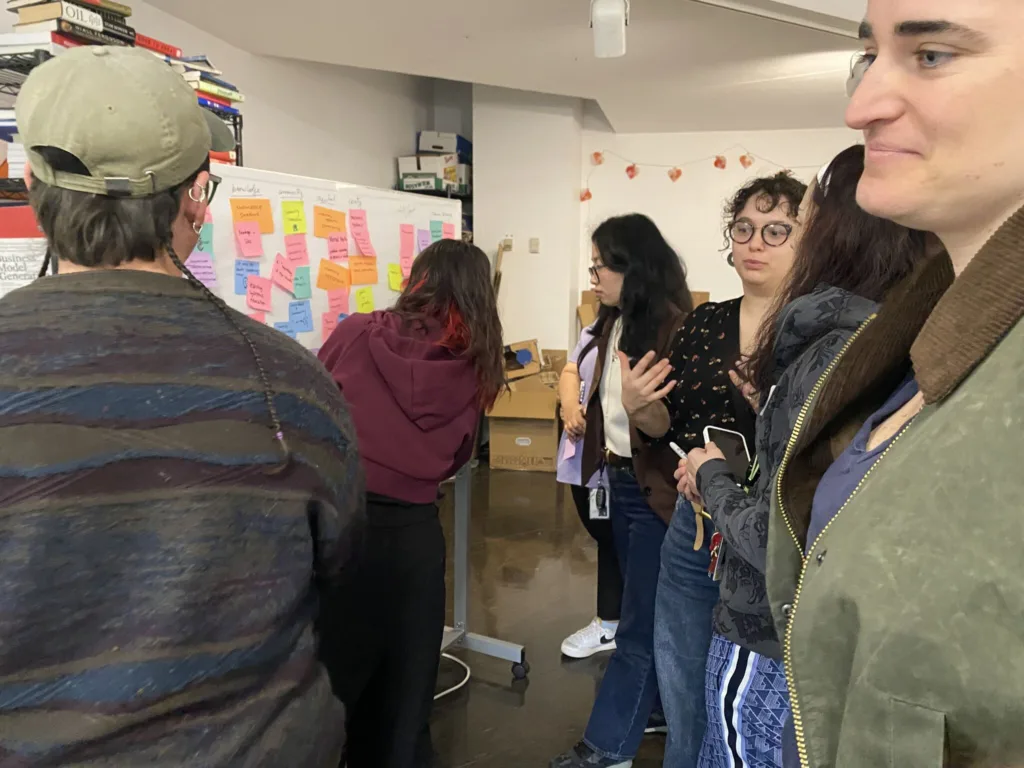 group standing in front of white board covered in multi-colored postit notes