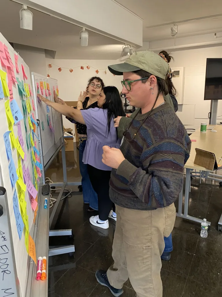 person standing in front of white board covered in multi-colored postit notes