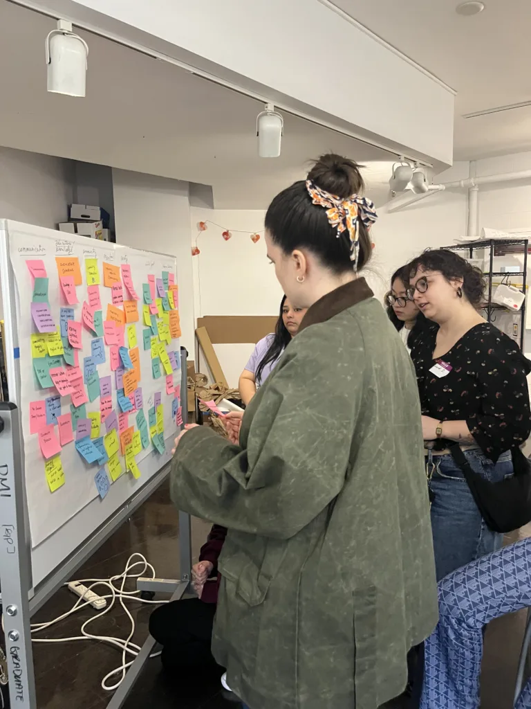 group standing in front of white board covered in multi-colored postit notes