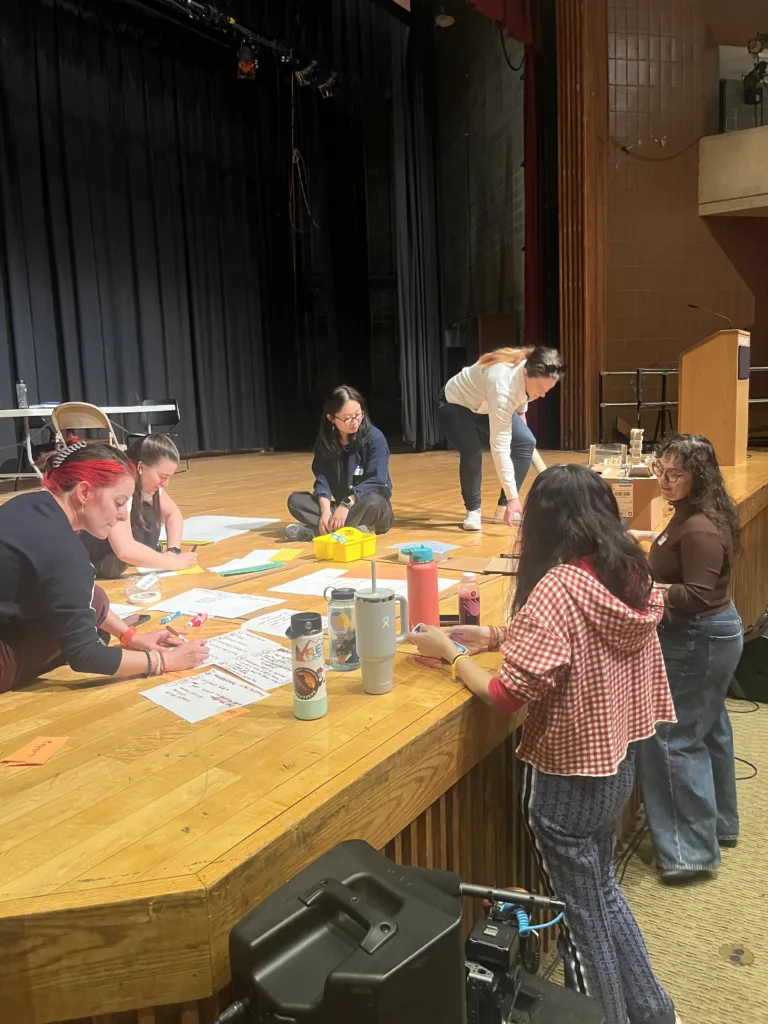 group sitting on stage writing on paper, Boston service jam 